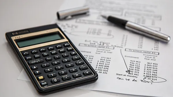 Calculadora, chave de carro e papelada de seguro sobre uma mesa de escritório