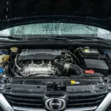 Carro híbrido sendo lavado em túnel de lava-rápido automático com jatos de água