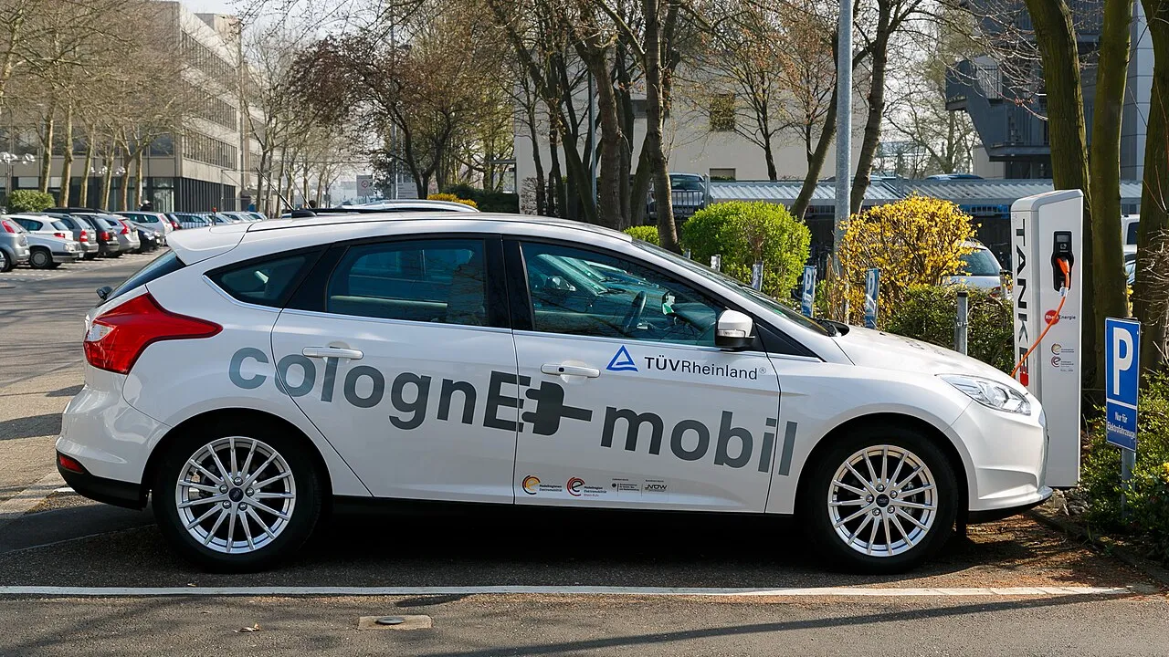 Ponto de recarga de carro elétrico em ambiente urbano, ilustrando a corrida por elétricos em falta no Brasil